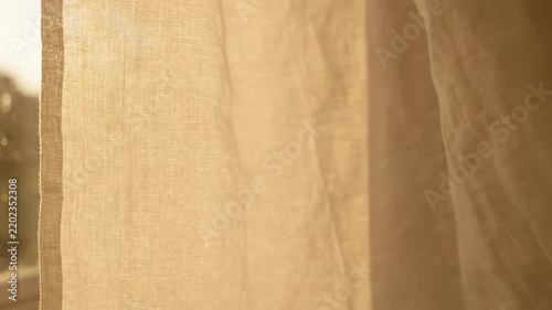 Soft diffused morning light illuminating the natural texture of a light-colored linen curtain, creating a peaceful and serene atmosphere with gentle warmth near a window
