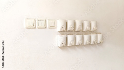a collection of white electrical wall fixtures mounted in two rows on a plain, off-white wall