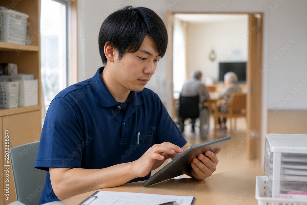 Fototapeta premium 介護職員がタブレットで介護記録を入力する場面