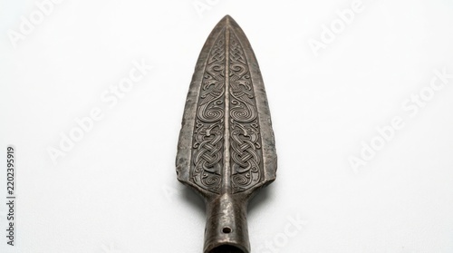Ancient spearhead with intricate carvings on white background