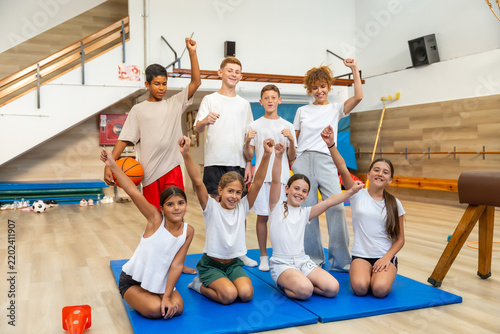Happy children and teacher celebrating success in school gym