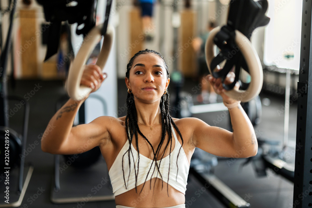 Fototapeta premium Focused young woman training with gymnastic rings