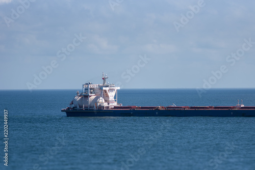 Obraz na płótnie Close-up view of an LNG-fueled bulk carrier underway on a calm blue sea, highlighting the large fuel tank positioned beside the ship's superstructure