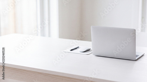 Modern minimal workspace with closed silver laptop on white wooden desk