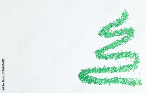 Abstract Christmas tree shape made of green glitter sequins on white background with copy space.