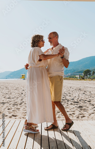 Senior couple dancing on beach enjoying retirement