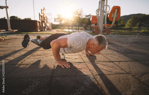Man with prosthetic leg exercising at sunset
