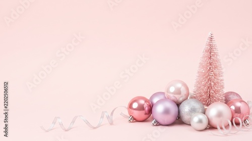 Pastel pink Christmas baubles and silver tinsel on blush background
