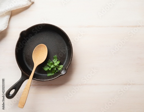 Cast iron pan with wooden spoon and fresh parsley