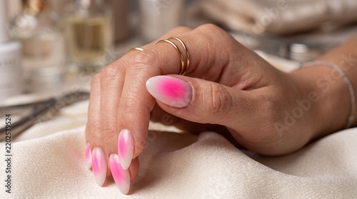 Manicured fingernails adorned with vibrant pink ombre polish display expert nail artistry and contemporary cosmetic care trends in a serene salon environment.