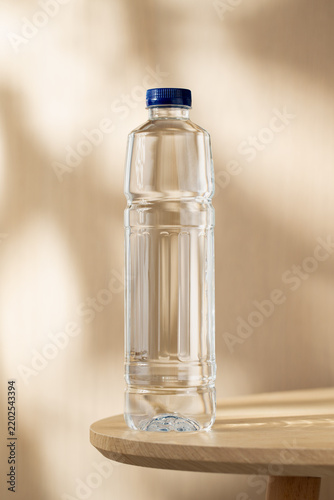 фотографія Clear bottled drinking water on a wooden table, illuminated by warm natural light and soft shadows, creating a clean setting for hydration, wellness, and everyday lifestyle concepts
