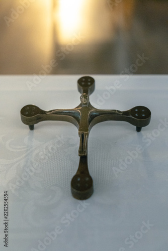 Antique metal cruciform candle holder with figure of Christ on white altar cloth