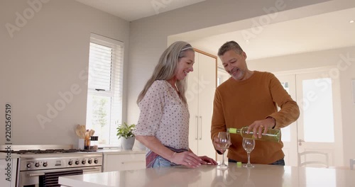 Senior couple enjoying wine together in modern kitchen, sharing joyful moment