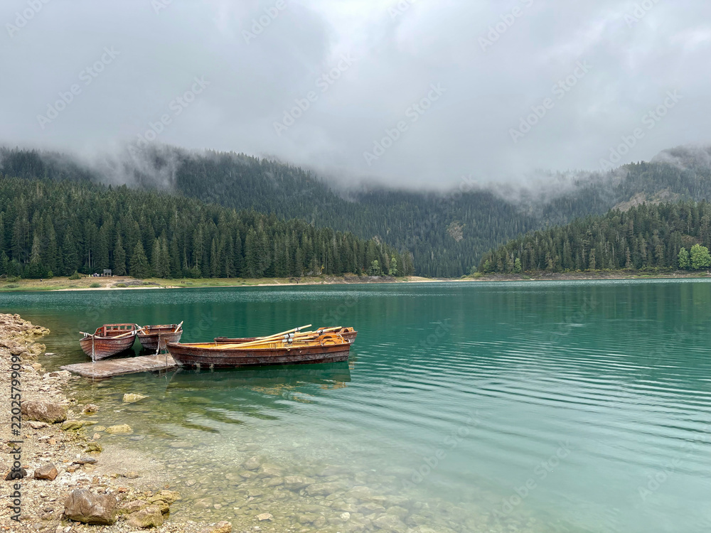 Naklejka premium Wooden boats on a misty forest lake in Durmitor Montenegro