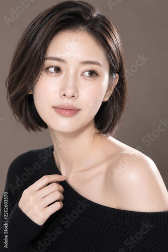 黒ニット姿で肩を見せるショートボブの日本人女性による上品な美容広告ポートレート