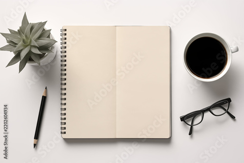 A high-angle shot of a modern entrepreneur's workspace, featuring a laptop and a notebook with blank pages.