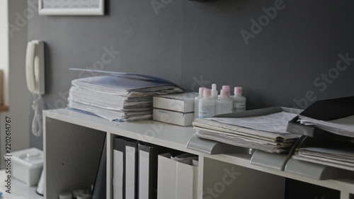Office documentation, paper stacks, archive binders, sanitizer bottles resting on administrative storage shelf. Clip suitable for corporate bureaucracy or medical workflow projects