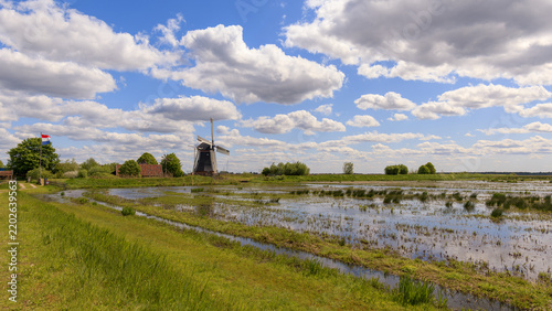 Traditional Dutch landscape with blue sky, clouds, floodplain polder and a classical Dutch windmill on a summer's day at the Onnerlanden, Onnen, Groningen, the Netherlands