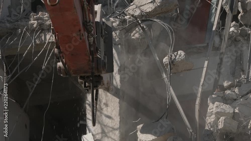 A crane demolishing a multi-story building in sunny weather.