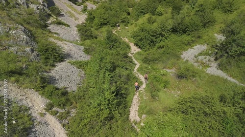 Trail runners running toward the rocks in beautiful sunny weather, filmed by a drone.