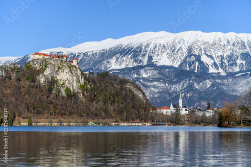 Bled Castle on a cliff above Lake Bled with St Martin church and snowy Karavanke mountains, winter, Slovenia