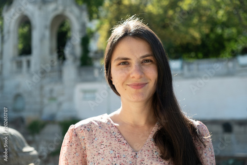 Portrait of attractive 34 year old brunette woman smiling gently in park