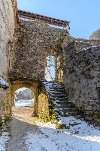Snow-covered stone steps and arched gateway inside a ruined medieval castle on a sunny winter day