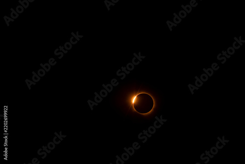 Принти на полотні Partial solar eclipse beginning: small bite taken from the orange sun with visib