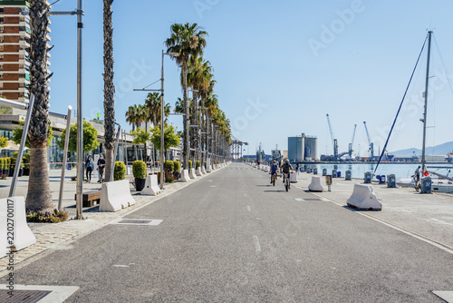 Malaga, Andalusia, Spain - 18 May 2020: View of the waterfront promenade with palm trees and people cycling during the easing of Covid lockdown restrictions.