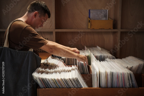 Fotografie Slow living vinyl browsing in record store as man explores analog music, retro hobby culture, physical media collecting and screen-free leisure