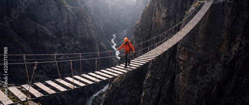 Mountaineer Crossing the Trift Bridge Wooden Suspension Path over Deep Mountain Gorge in Swiss Alps Gadmen Switzerland