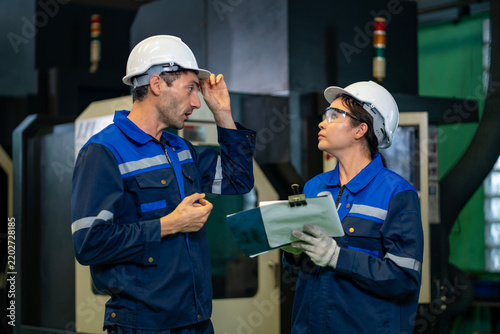 Team of industrial worker is checking the setup value of  metal casting machine by automated monitor while working inside factory for safety industry