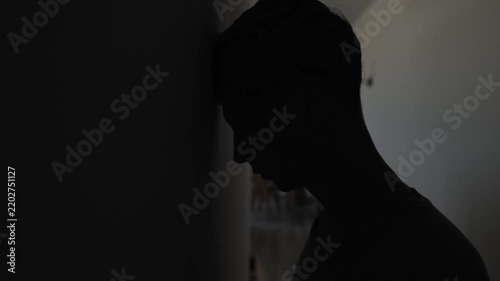 Desperate man hitting head against wall with dark copy space