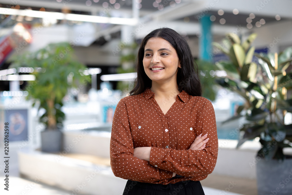 Obraz premium Confident woman smiling with arms crossed in modern office