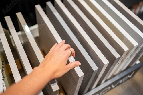 Woman touches countertop samples while choosing material in furniture showroom. Home renovation and interior design choice captured with selective focus and shallow depth of field