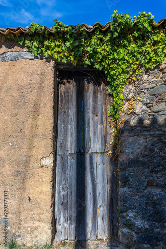 A weathered wooden door is framed by an old stone wall