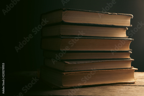 Stack of old books on wooden table. Retro style toned picture