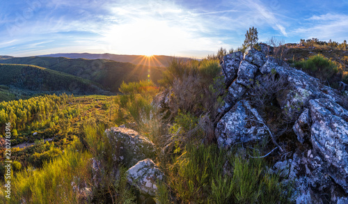 A bright sunset illuminates rugged rocky terrain