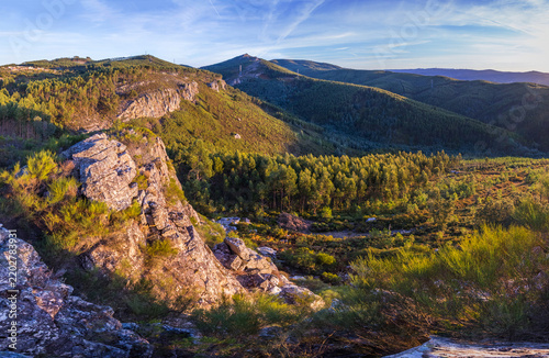 A scenic aerial view captures rugged rocky cliffs and vast rolling green hills