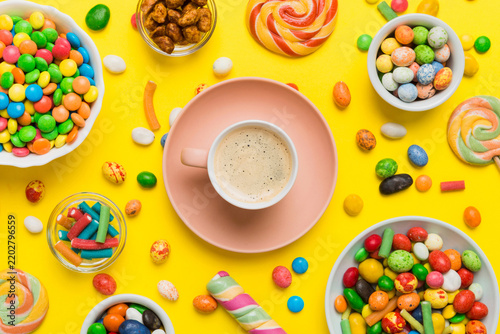 Coffee cup with chocolates and colored candy. Top view on table background with copy space