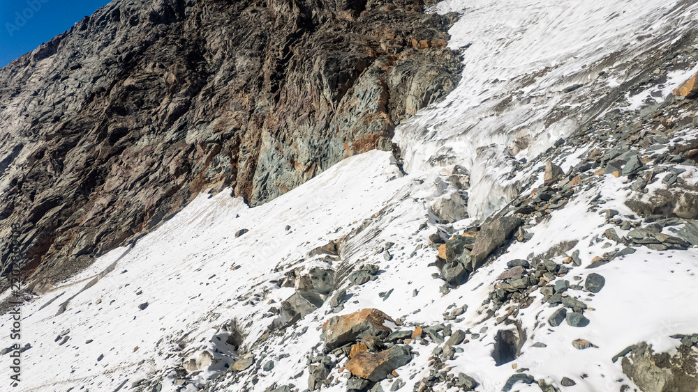 Obraz premium Crevasse view during the Grossglockner hike, alpine mountain landscape with glacier and rugged rocky terrain, snowfields, and a stone cairn in High Tauern, national park