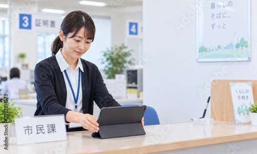 市役所の市民課窓口でタブレットを確認しながら受付業務を行う日本人女性職員