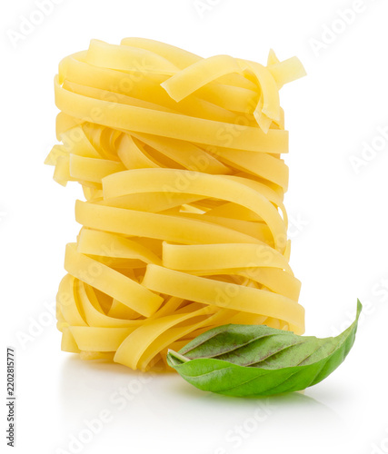 Dry tagliatelle pasta nest with basil leaf isolated on white background