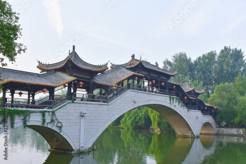 Traditional Chinese Covered Bridge with Red Lanterns Over Park Lake