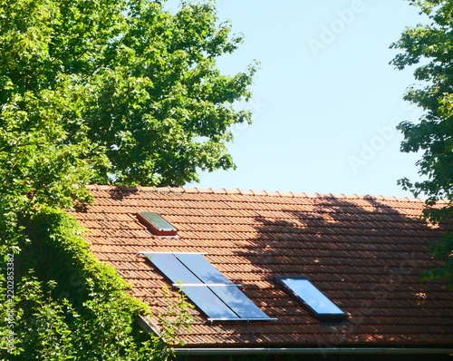 Photovoltaic energy: photovoltaic solar panels on an old tiled roof in a sunny day with blue sky