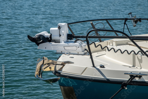 Electric trolling motor mounted on the stern of a recreational boat with propeller raised above water.
