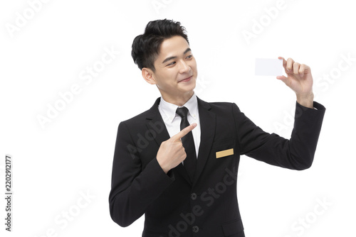 Quadro su tela Smiling Businessman in Suit Pointing at Blank White Card