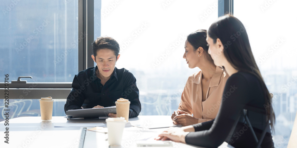 Fototapeta premium Diverse corporate colleagues brainstorming, discuss together project with laptop computer, document in office meeting. Male, female employees business meeting in office conference room
