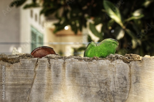 Broken glass shards cemented onto the top of a concrete boundary wall. Shards of glass are embedded in the mortar of a wall for security measure to discourage intruders or animals from climbing