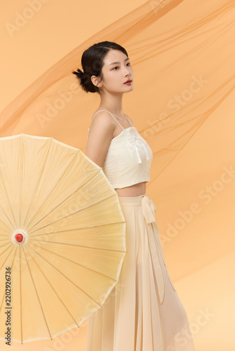 Photography Elegant young woman with traditional paper parasol in soft beige studio portrait